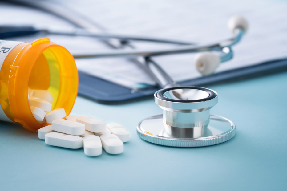 bottle of pills, clip board, and stethoscope on a doctors desk